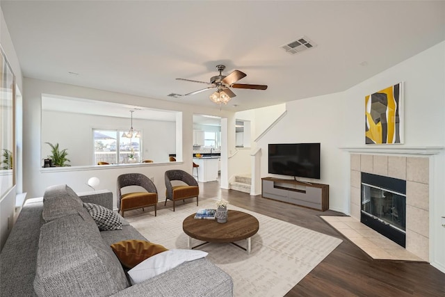 living room with a tile fireplace, ceiling fan, and light hardwood / wood-style flooring