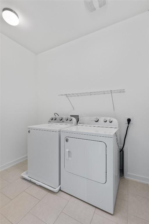 laundry room with independent washer and dryer and light tile patterned floors