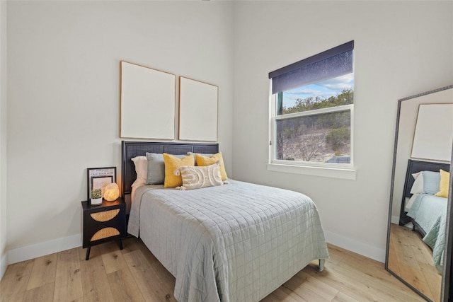 bedroom featuring light wood finished floors and baseboards