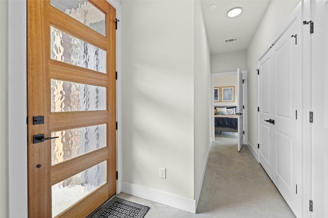 hall with baseboards, visible vents, and finished concrete floors