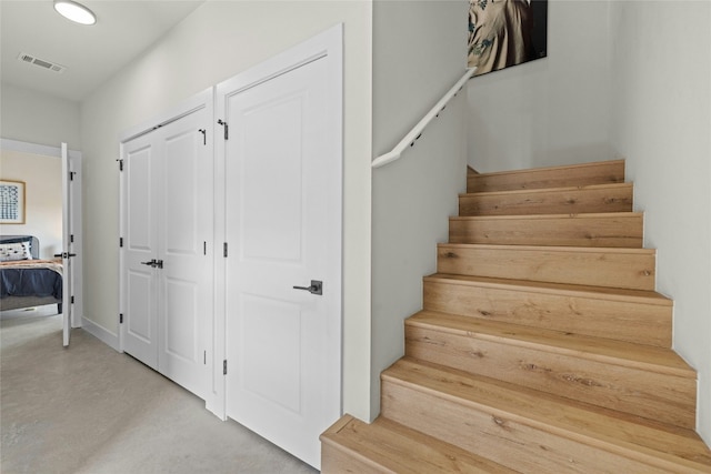 staircase with visible vents and finished concrete flooring