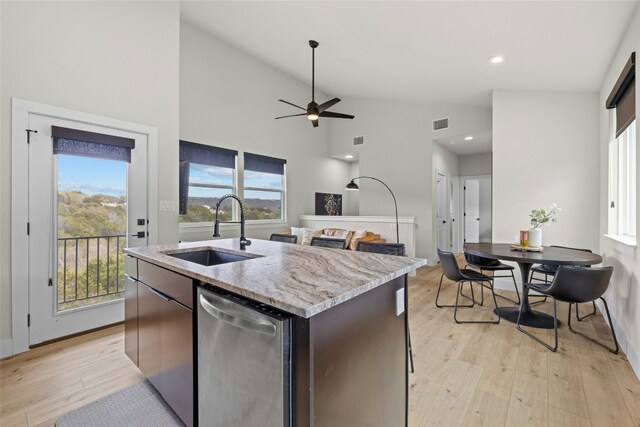 kitchen featuring sink, dishwasher, a kitchen island with sink, and light hardwood / wood-style flooring