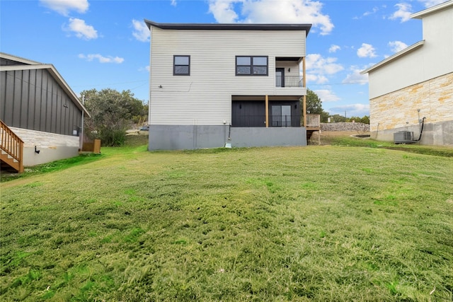 rear view of house featuring a balcony and a yard