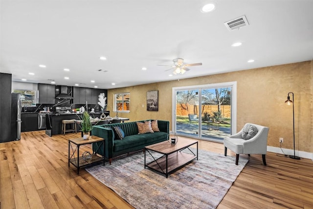 living room with ceiling fan and light hardwood / wood-style flooring