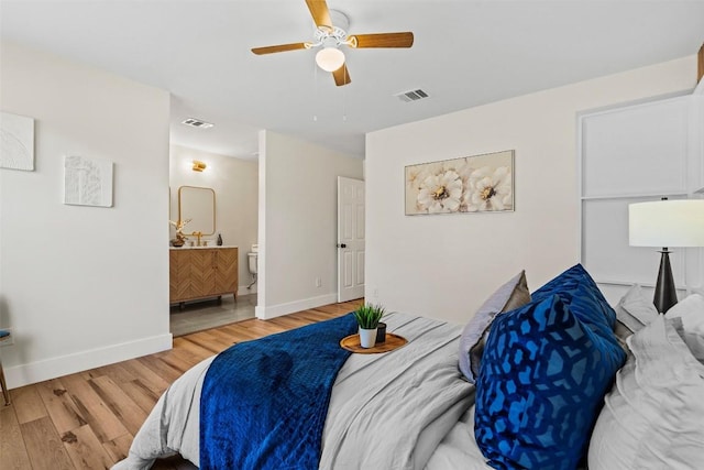 bedroom with ceiling fan, ensuite bath, and light wood-type flooring