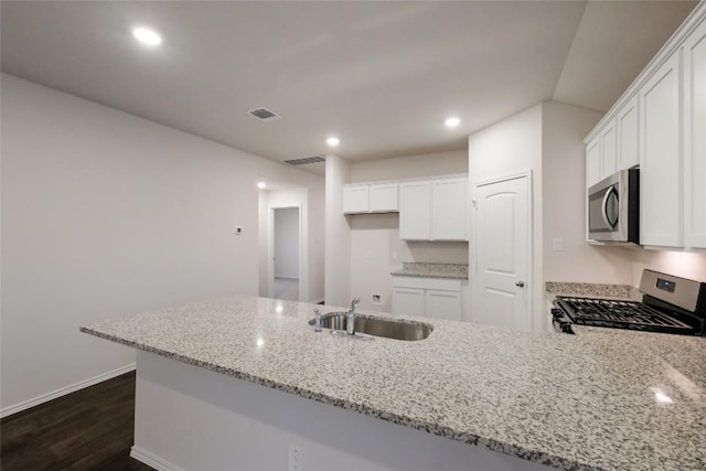 kitchen with white cabinetry, stainless steel appliances, light stone countertops, and sink