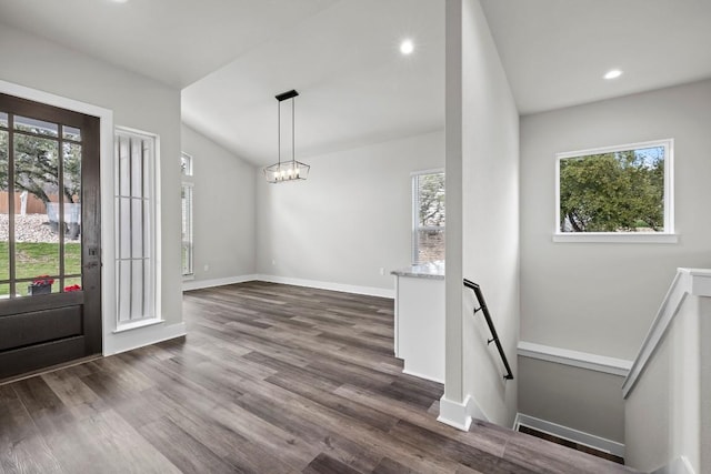 foyer entrance featuring dark hardwood / wood-style flooring, vaulted ceiling, and a notable chandelier