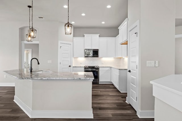 kitchen featuring sink, decorative light fixtures, stainless steel appliances, a kitchen island with sink, and white cabinets