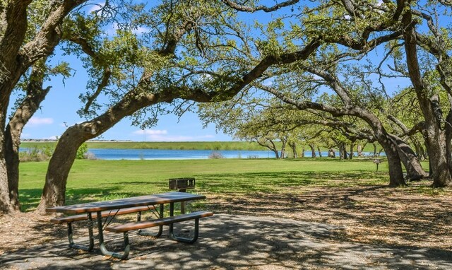 view of home's community with a water view and a lawn