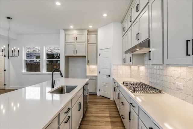 kitchen with pendant lighting, dishwasher, sink, decorative backsplash, and light wood-type flooring