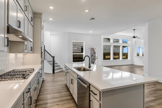 kitchen with sink, gray cabinetry, an island with sink, stainless steel appliances, and decorative backsplash