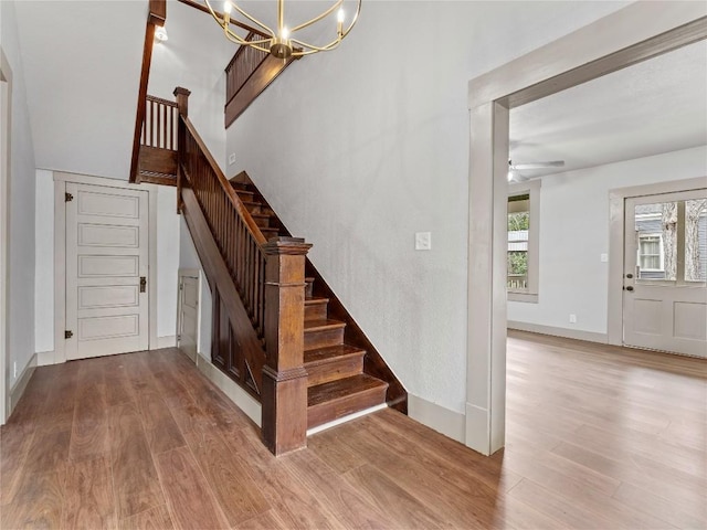 stairway with hardwood / wood-style flooring and ceiling fan with notable chandelier