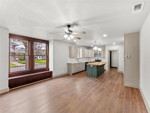 kitchen with gray cabinets, hanging light fixtures, a center island, tasteful backsplash, and stainless steel electric stove