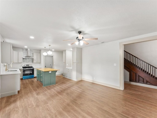 kitchen with a kitchen island, butcher block countertops, sink, electric range, and wall chimney exhaust hood