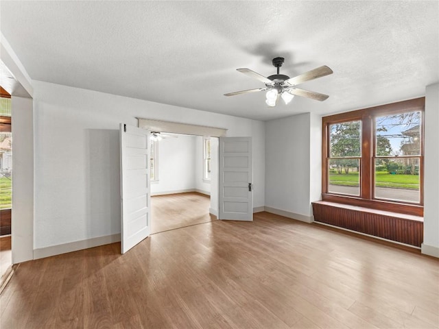 interior space with ceiling fan, a textured ceiling, and light hardwood / wood-style floors