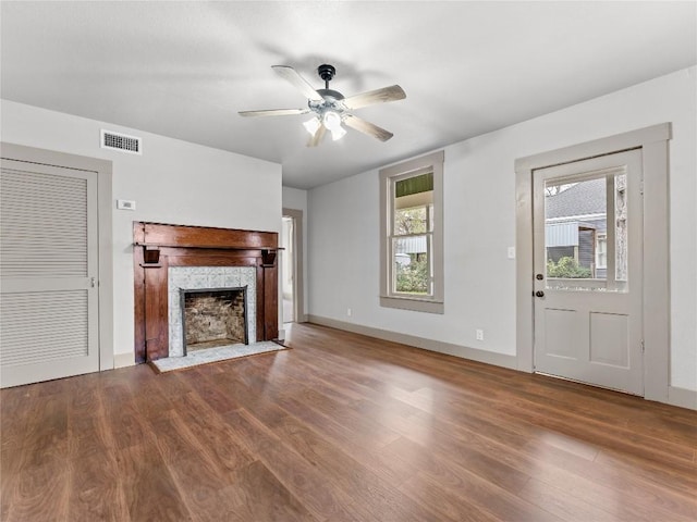 unfurnished living room featuring hardwood / wood-style flooring, ceiling fan, and a fireplace