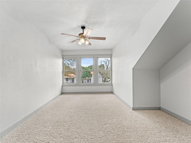 additional living space with ceiling fan, light carpet, and a textured ceiling