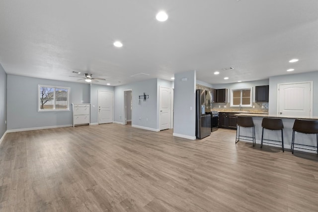 living room featuring sink, light hardwood / wood-style floors, and ceiling fan