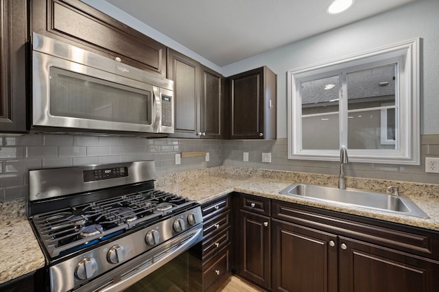 kitchen with appliances with stainless steel finishes, sink, dark brown cabinets, and backsplash