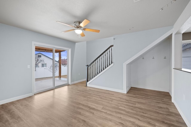 unfurnished living room with a textured ceiling, light hardwood / wood-style floors, and ceiling fan