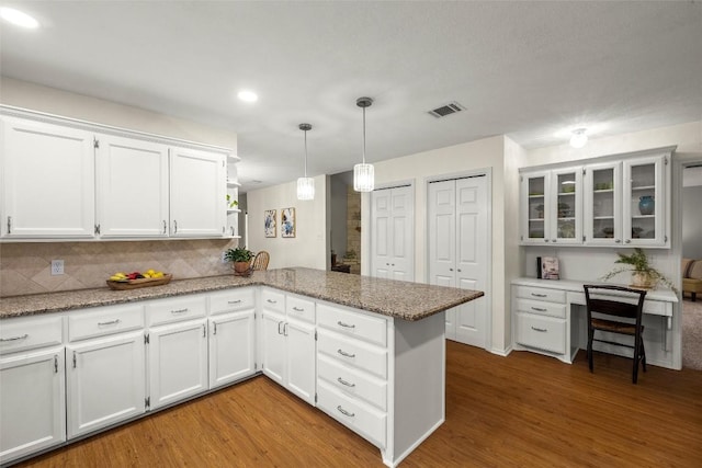 kitchen with pendant lighting, kitchen peninsula, white cabinets, and light wood-type flooring