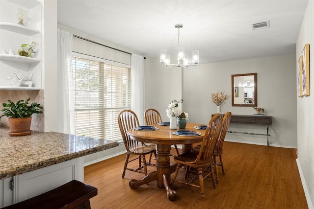 dining area with an inviting chandelier and light hardwood / wood-style flooring