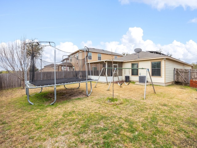 back of property featuring a trampoline, cooling unit, a lawn, and a sunroom