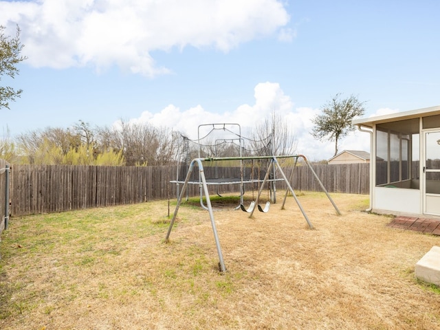 view of jungle gym featuring a sunroom, a trampoline, and a lawn