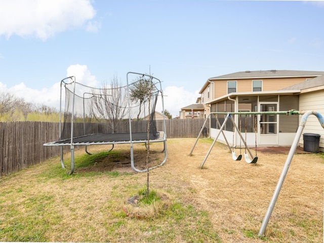 view of jungle gym featuring a trampoline, a yard, and a sunroom