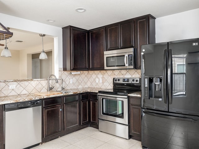 kitchen with light stone counters, stainless steel appliances, sink, and decorative backsplash