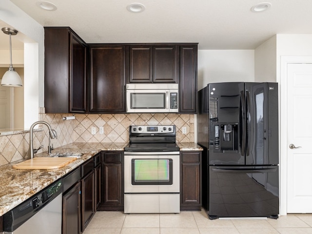 kitchen featuring appliances with stainless steel finishes, pendant lighting, sink, light stone counters, and dark brown cabinets