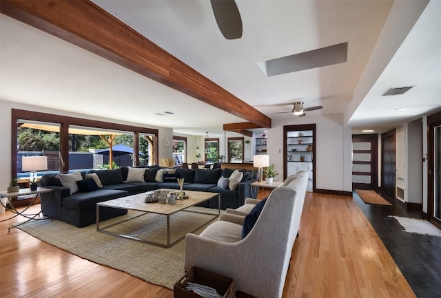 living room featuring ceiling fan, hardwood / wood-style floors, and beam ceiling