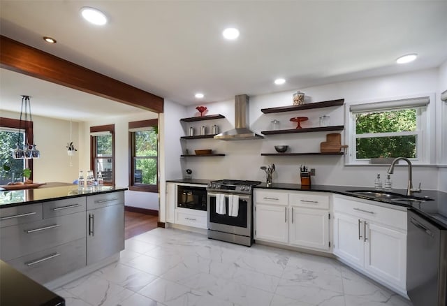 kitchen featuring wall chimney range hood, sink, white cabinetry, beam ceiling, and stainless steel appliances