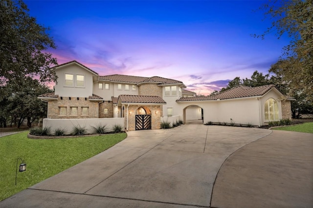 mediterranean / spanish-style house featuring a garage and a lawn