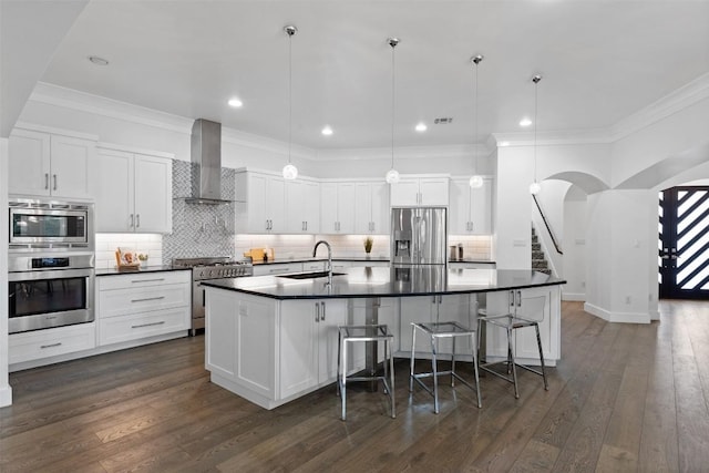 kitchen with appliances with stainless steel finishes, sink, wall chimney range hood, and decorative light fixtures