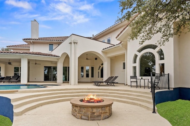 back of property with a fire pit, a patio area, and ceiling fan