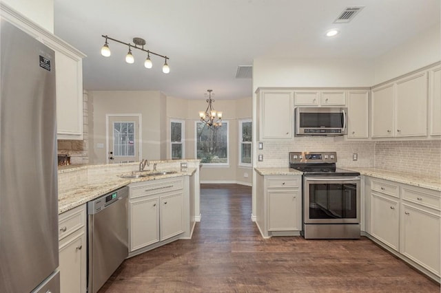 kitchen with a peninsula, tasteful backsplash, appliances with stainless steel finishes, and a sink