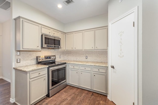 kitchen with dark wood-type flooring, visible vents, appliances with stainless steel finishes, backsplash, and light stone countertops