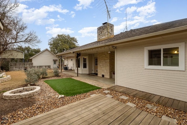 back of house featuring a chimney, an outdoor fire pit, a patio area, fence, and cooling unit