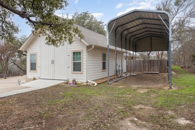 view of side of home with a shingled roof, a detached carport, and fence