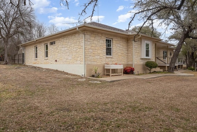 view of side of home with stone siding and a lawn