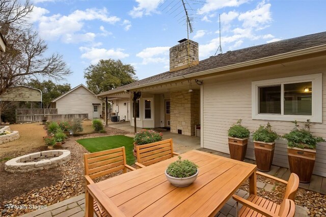 rear view of property with a patio, a fire pit, central AC, outdoor dining space, and a chimney