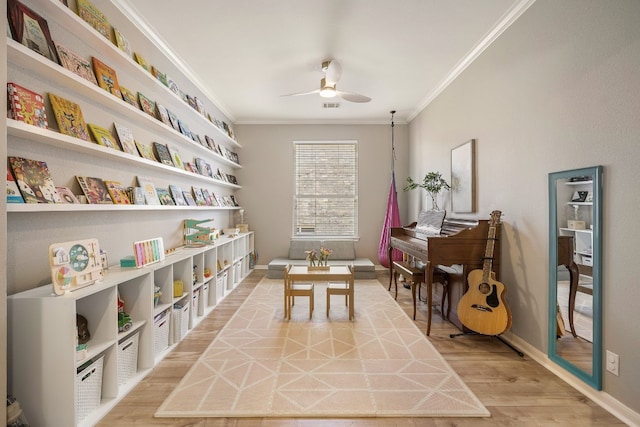 playroom featuring crown molding, ceiling fan, and wood-type flooring