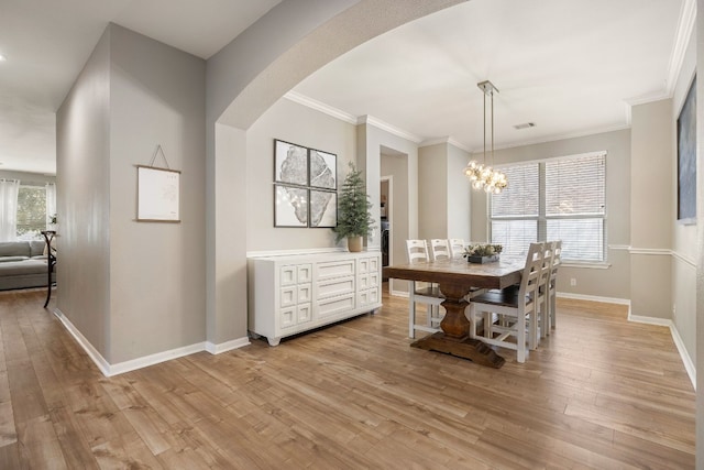 dining space with ornamental molding, plenty of natural light, a notable chandelier, and light hardwood / wood-style floors