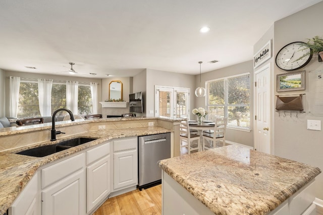 kitchen with sink, white cabinetry, light stone counters, a center island, and stainless steel dishwasher