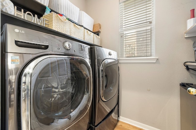 laundry room with independent washer and dryer and light hardwood / wood-style flooring