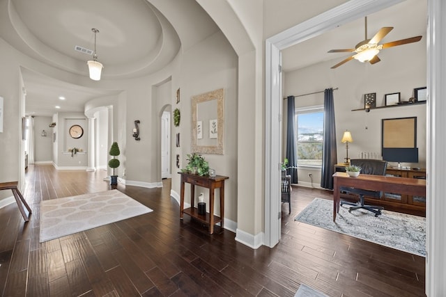 foyer featuring visible vents, arched walkways, and dark wood-style flooring