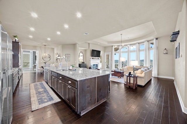 kitchen featuring open floor plan, a sink, dark brown cabinetry, and a large island