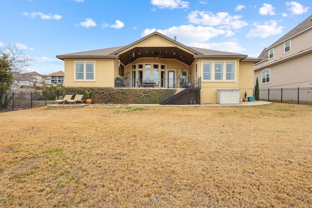 back of property featuring a fenced backyard, a lawn, a ceiling fan, and stucco siding