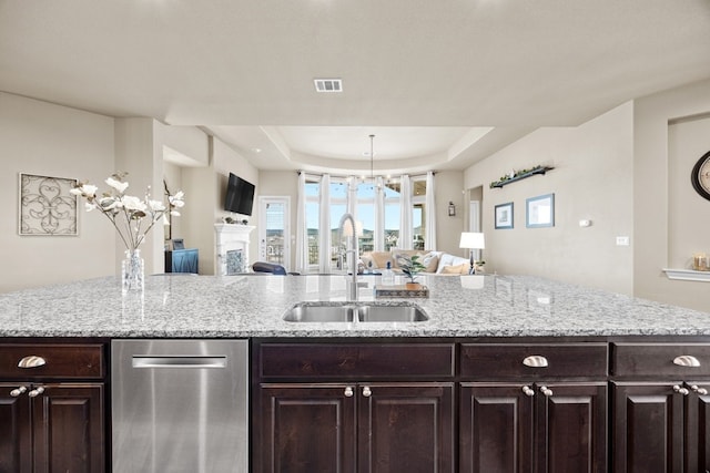 kitchen with a tray ceiling, visible vents, open floor plan, and a sink